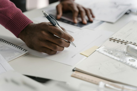 Person writing notes on documents at a desk.