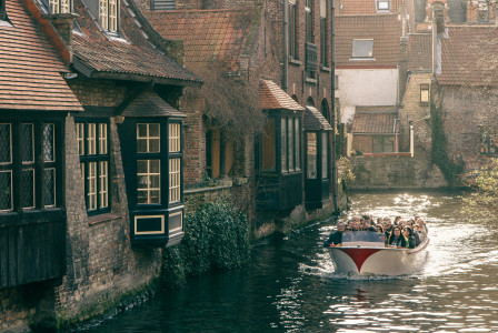 An illustrative photo of a boat packed with tourists passing houses.