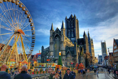 An illustrative photo of people walking near a ferris wheel and a church.