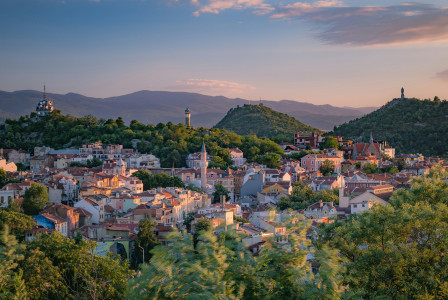 An illustrative photo of a small town surrounded by trees and mountains.