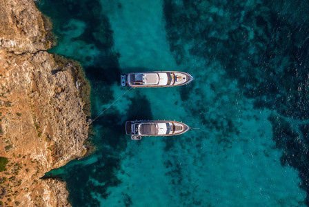 Photo by Unsplash An illustrative photo of two white boats in a body of water near a rocky shore.