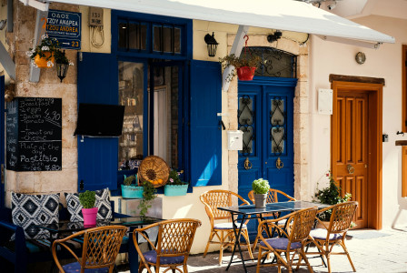 Photo by Unsplash An illustrative photo of armchairs outside a café with blue doors.