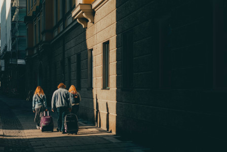 An illustrative photo of three people walking on the sidewalk near the walls.