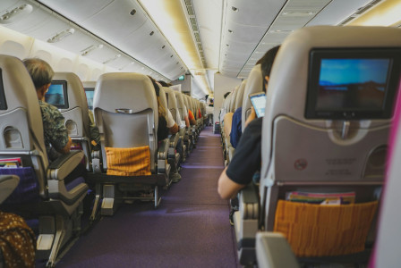 An illustrative photo of people sitting on chairs inside airplane.
