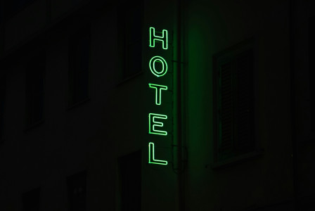 An illustrative photo of a hotel sign lit up in the dark.