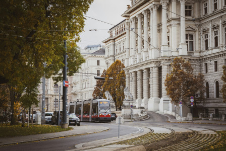 An illustrative photo of a tram going near a big white building.