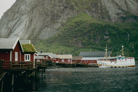 An illustrative photo of a boat at a dock in front of a mountain.