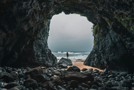 An illustrative photo of a person standing on a rocky beach.
