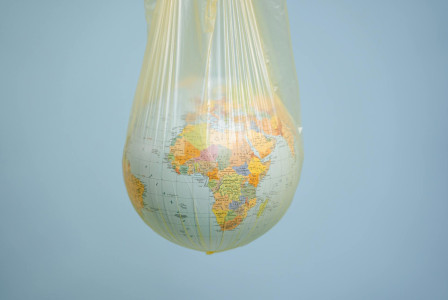 World globe wrapped in a plastic bag against a plain background.