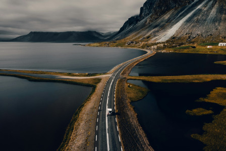 An illustrative photo of a gray concrete road near mountain.