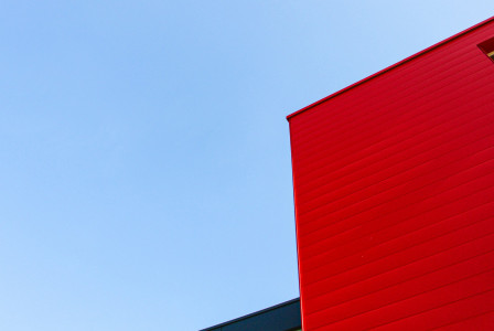 Colour photograph of a grey and red building against a blue sky