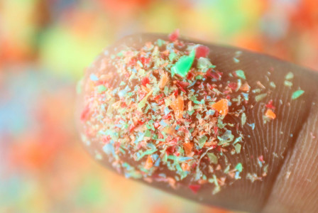 Finger with colorful microplastics