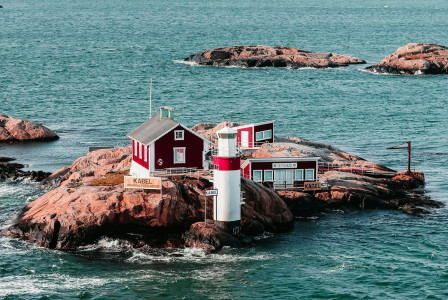a-red-and-white-house-sitting-on-top-of-a-rock-in-the-ocean