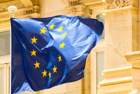 European Union flag waving in front of building. 