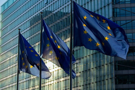 Three European Commission flags on poles.