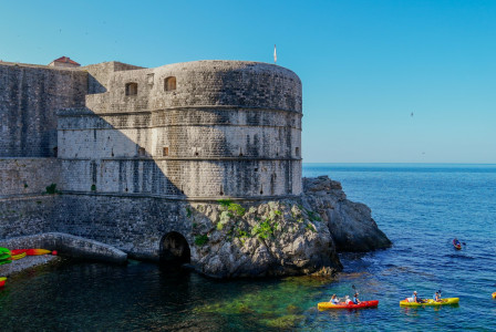 a-group-of-people-in-kayaks-on-the-water-near-a-castle-