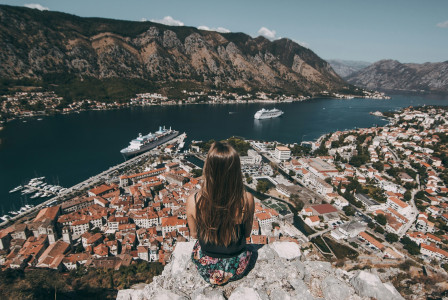 woman-sitting-on-top-of-cliff-facing-buildings
