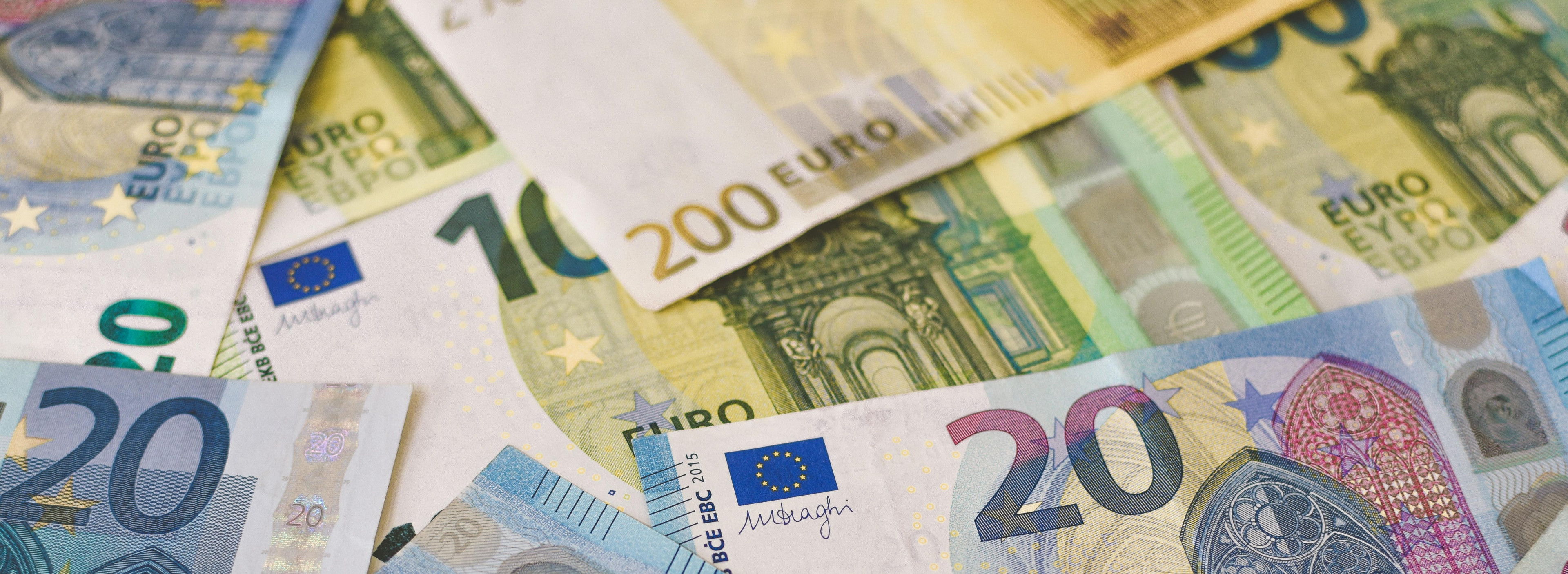 A photo presenting a close-up view of overlapping euro banknotes of various denominations.