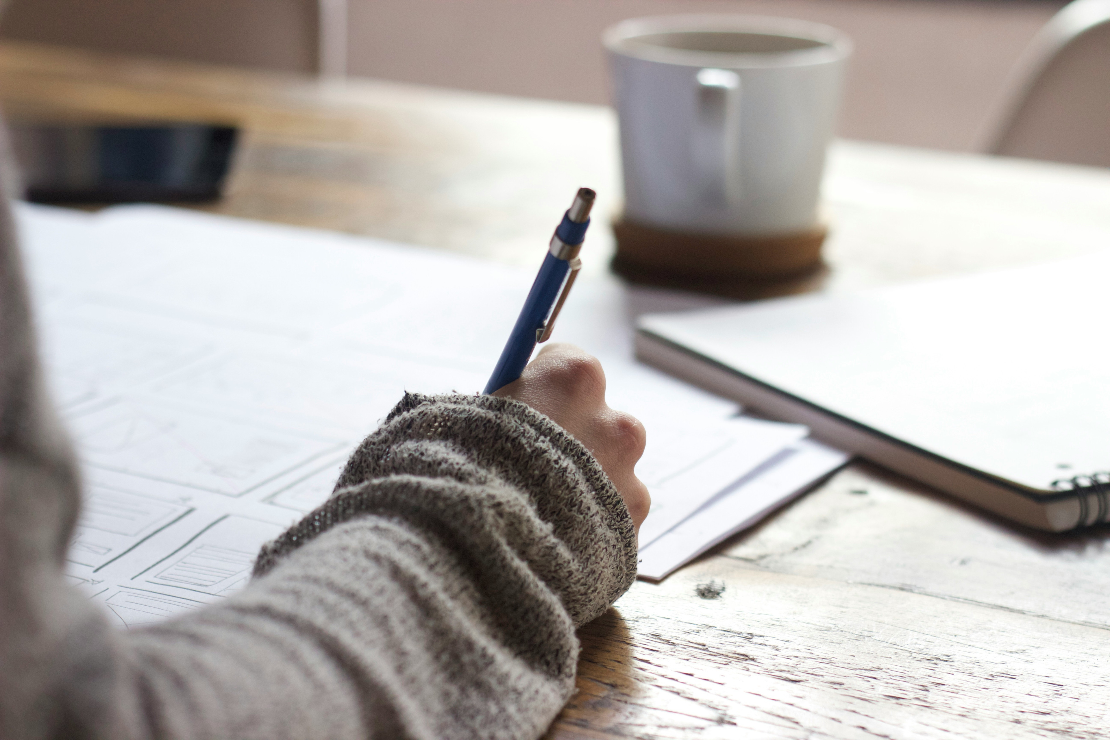 This picture presents a person writing at a desk.