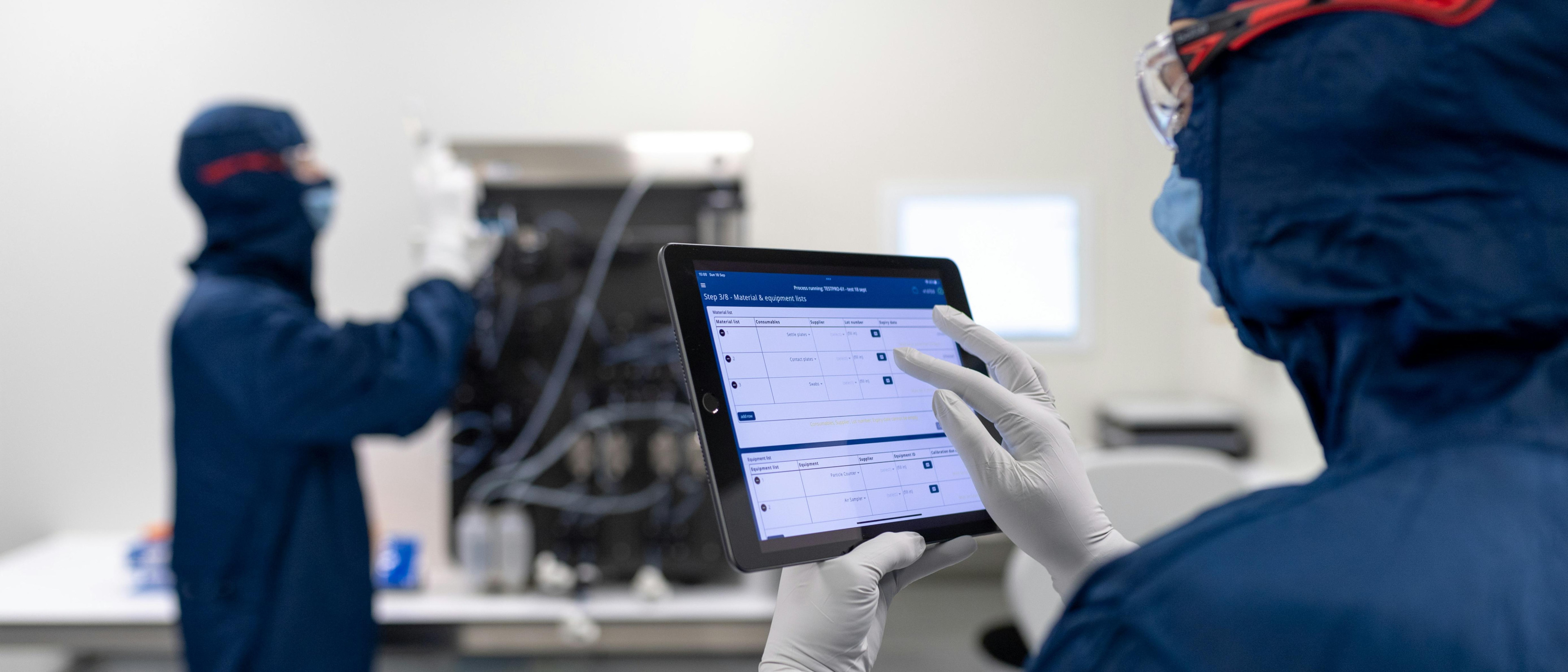 A photo presenting a technician using a tablet checklist in a cleanroom lab.