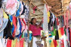 Person selecting clothes from colourful garments hanging in a small market stall.