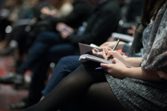 Audience members taking notes during a conference.