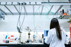 Researcher working in a laboratory with equipment and cables.