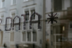 Window with the word “DATA” in dotted lettering, reflected over a blurred street scene.