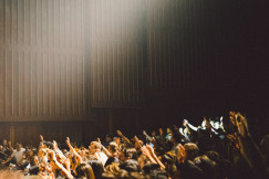 People raising their hands inside auditorium.