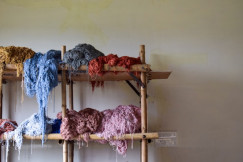 Bunches of colorful yarn on a wooden shelf.
