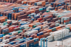 Aerial view of a large container terminal with hundreds of stacked shipping containers and transport vehicles, representing global logistics and international trade.