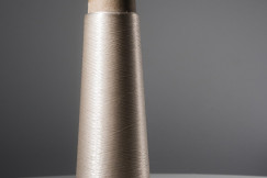 Spool of translucent thread on a cardboard cone with a gray background.