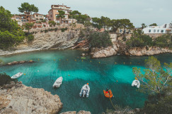 people-in-white-and-orange-boat-on-water-near-brown-rock-formation-during-daytime