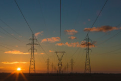 A graphic presenting high-voltage power lines stretch across an open landscape at sunset.