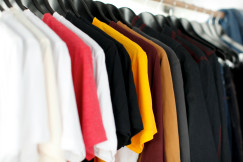 Clothes in various colors hanging on a rack.