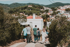 A group of people strolling down a path in a charming European village with lush greenery.