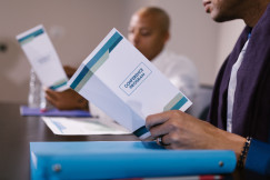 Attendees reading conference programs during a business meeting.
