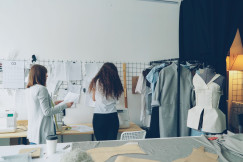 Fashion designers working on clothing sketches and patterns in a modern studio.