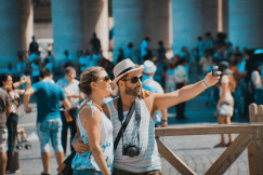 Photo presenting a couple taking a selfie at a crowded tourist landmark.