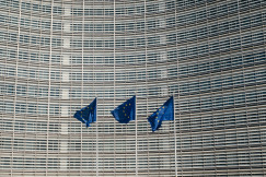 Photo presenting European Union flags in front of a modern office building facade.