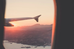 A picture presents an airplane wing above the landscape at sunset.