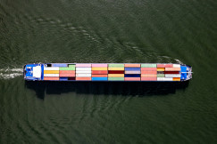 The picture presents a cargo ship carrying colorful shipping containers on the water.