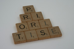 A photo presenting wooden letter tiles arranged in a pyramid to spell "prioritise".
