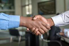 Two business professionals shaking hands during a meeting, representing networking, partnership building and international business collaboration in the textile and fashion industry.