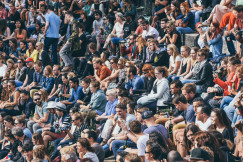 A picture presents a large crowd of people sitting together outdoors.