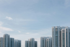 A photo presents modern residential towers under a cloudy sky.