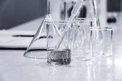 Laboratory glassware on a lab bench with a pipette in a transparent beaker containing a clear liquid.