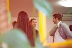 A photo presents people talking during an indoor meeting.