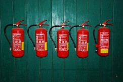 A photo presents fire extinguishers mounted on a green wall.