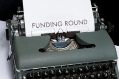 Green and white braille typewriter with paper saying ‘Funding round’. 